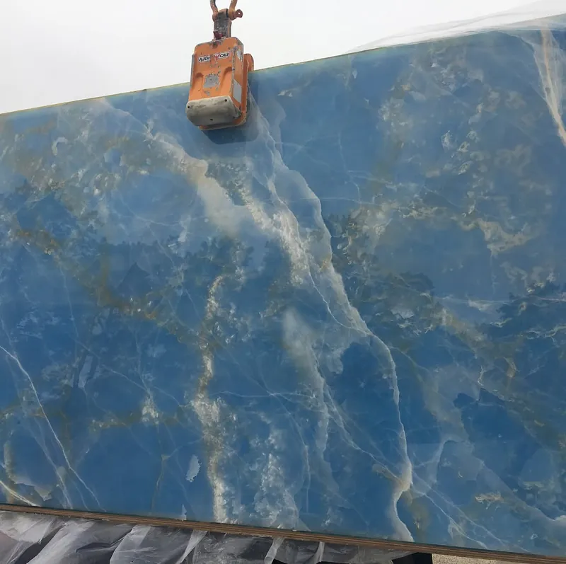 Blue onyx slab hanging from the lifting clamp at the yard in South Yarmouth