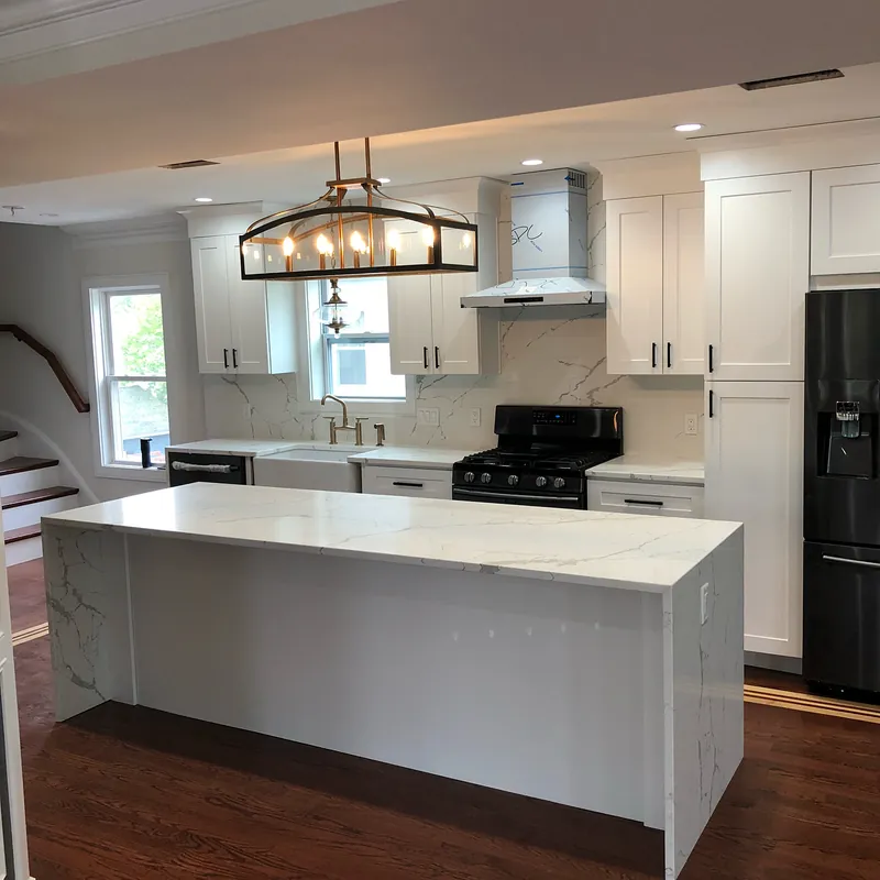 Calacatta quartz island with waterfall ends under a lantern chandelier, white shaker cabinets, Osterville, MA