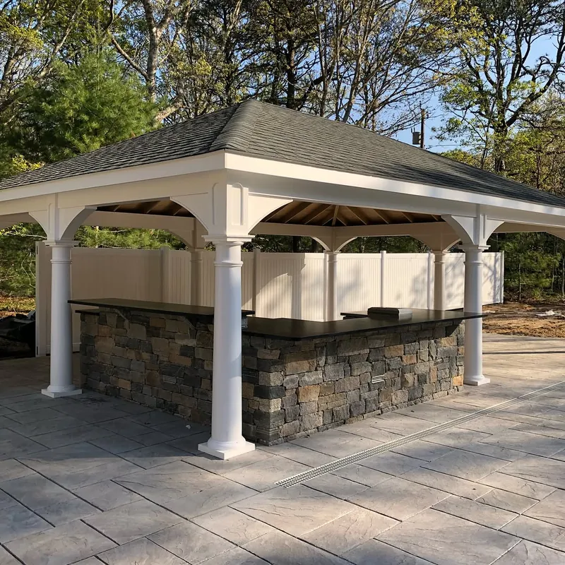 Outdoor kitchen under a white pergola by the pool: honed Jet Mist granite counters on a stone base, Yarmouth, MA
