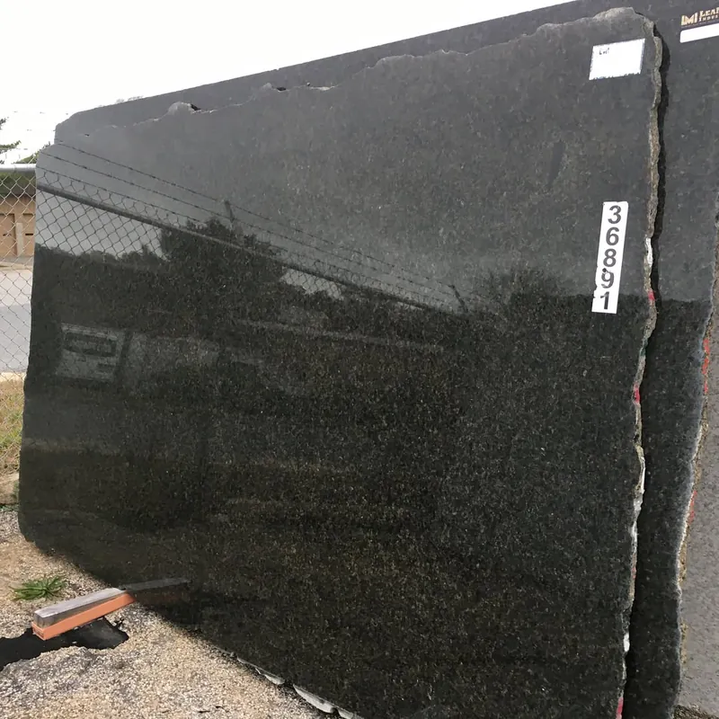 Dark polished level 1 granite slab with its yard tag, reflecting the fence line at 18 Fruean Way