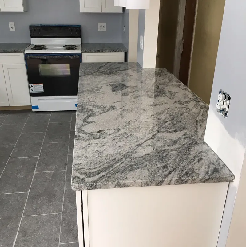 Silver Cloud granite island over a gray tile floor, white cabinets behind, Saugus, MA