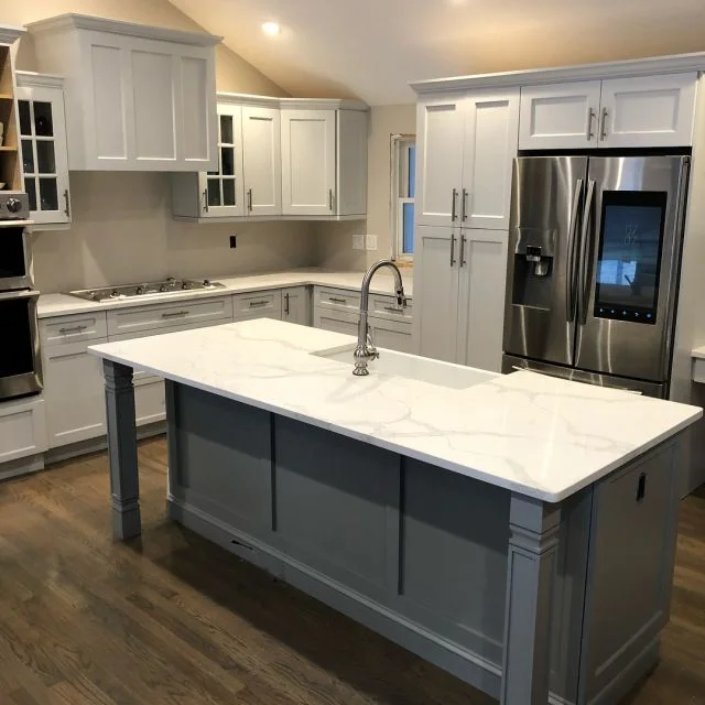 Calacatta quartz island on a grey base in a tall white kitchen