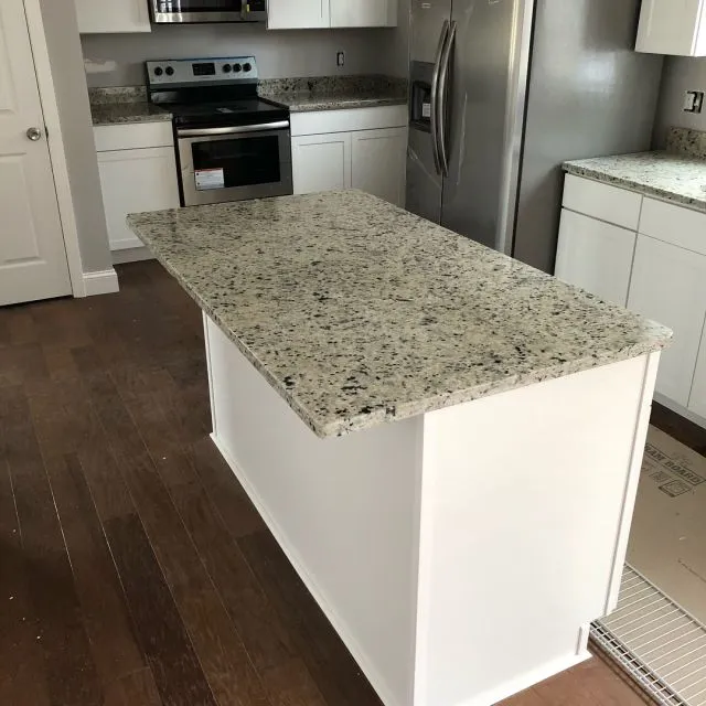 White speckled granite island and matching perimeter counters with stainless appliances, installed on Cape Cod
