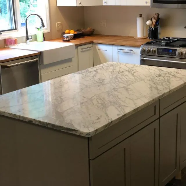 Kitchen island with Carrara-style grey veining, farmhouse sink and butcher-block perimeter counters